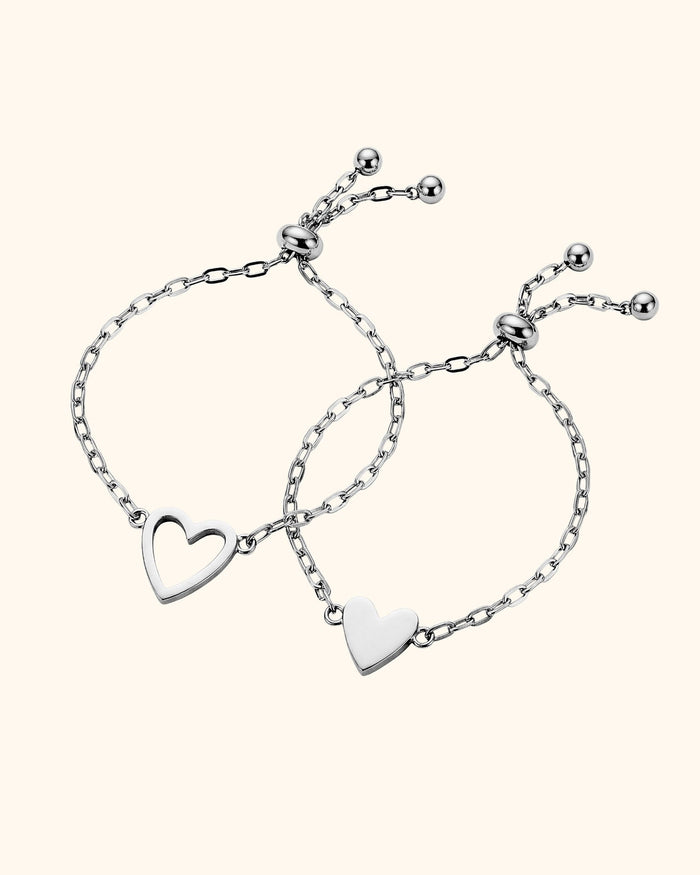 Two silver mother-daughter heart bracelets: an open heart for mom and a filled heart for her daughter, each with an adjustable slider and two small beads