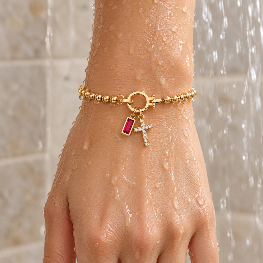 Gold cross charm birthstone bracelet worn under shower water, waterproof and tarnish resistant
