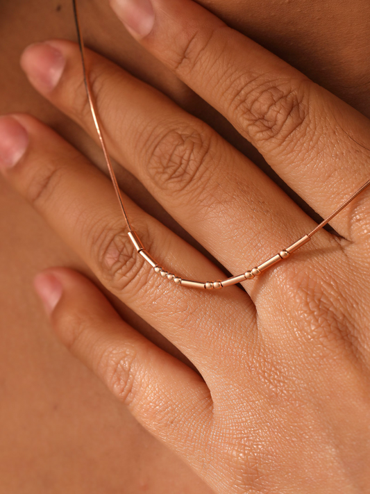 Rose-colored Morse necklace across fingers